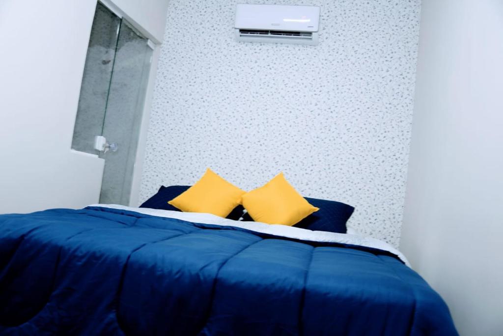 un letto blu con cuscini gialli in una camera da letto di POUSADA FLAT MÃE RAINHA a Maceió