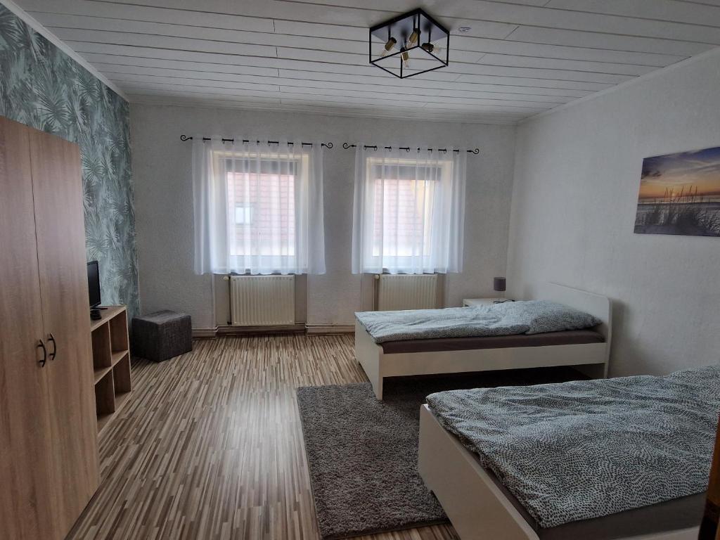 a bedroom with two beds and a tv and two windows at Ferienwohnung/Monteurunterkunft Leopolshall in Staßfurt