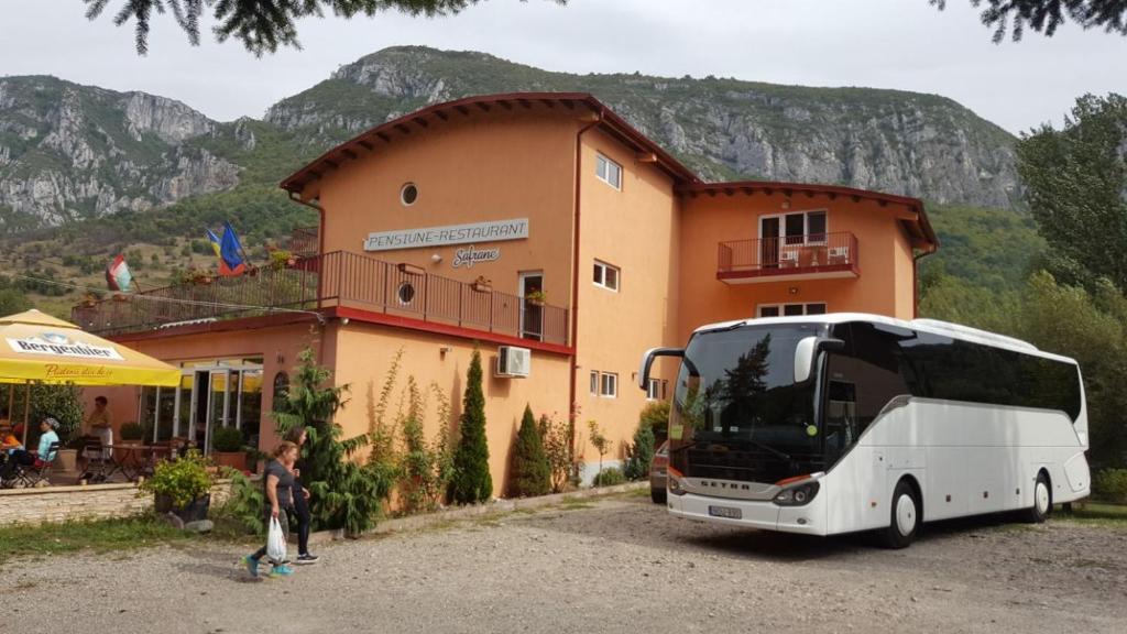a white bus parked in front of a building at Pensiune Safrane in Băile Herculane