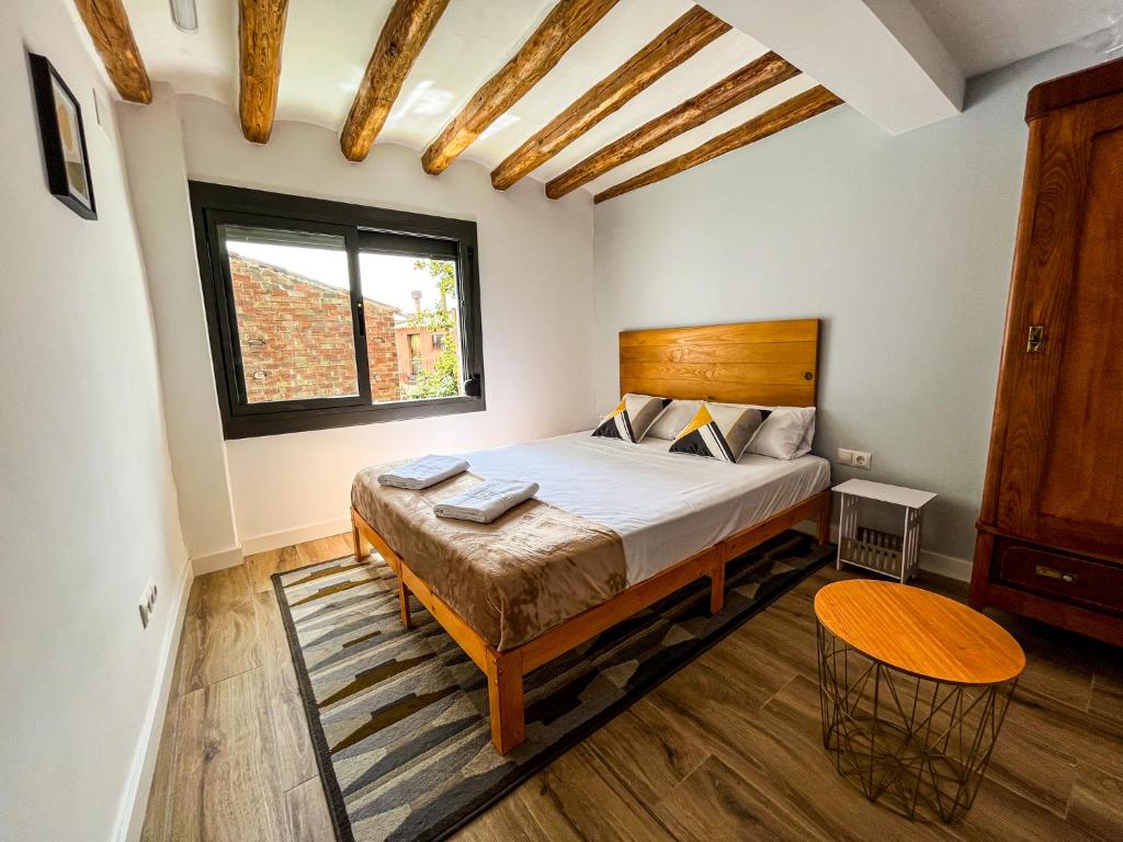 1 dormitorio con 1 cama con cabecero de madera y mesa en Casa Yama - Renovated House in the Center of Berga, en Berga