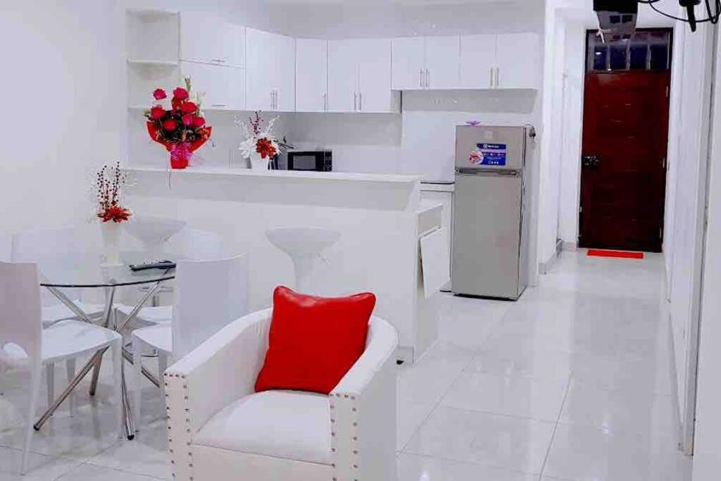 a white kitchen with a white chair with a red pillow at Moderno y nuevo departamento “Casa Blanca” in Trujillo