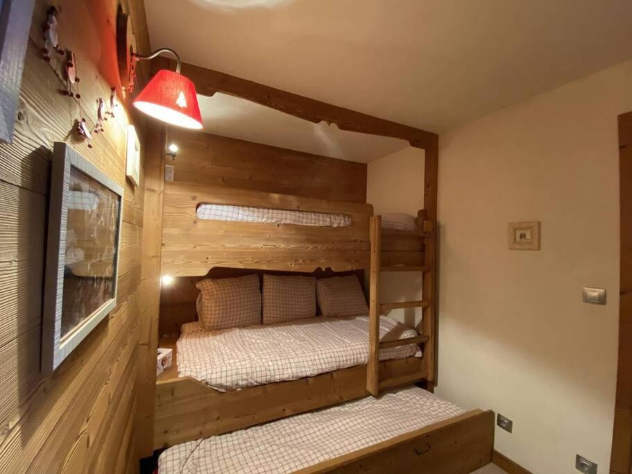 two bunk beds in a room with a red lamp at Alpe d&#39;Huez Houses - Chalet des Roches - Duplex, SUR les pistes de 3 chambres ! in LʼHuez