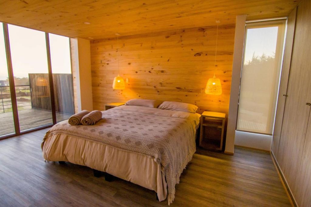 um quarto com uma cama num quarto com janelas em Lafk Lodge em Pichilemu