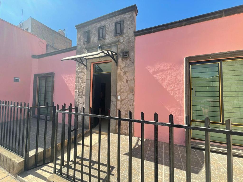 een roze gebouw met een hek ervoor bij CASA VICTORIA in Tequila