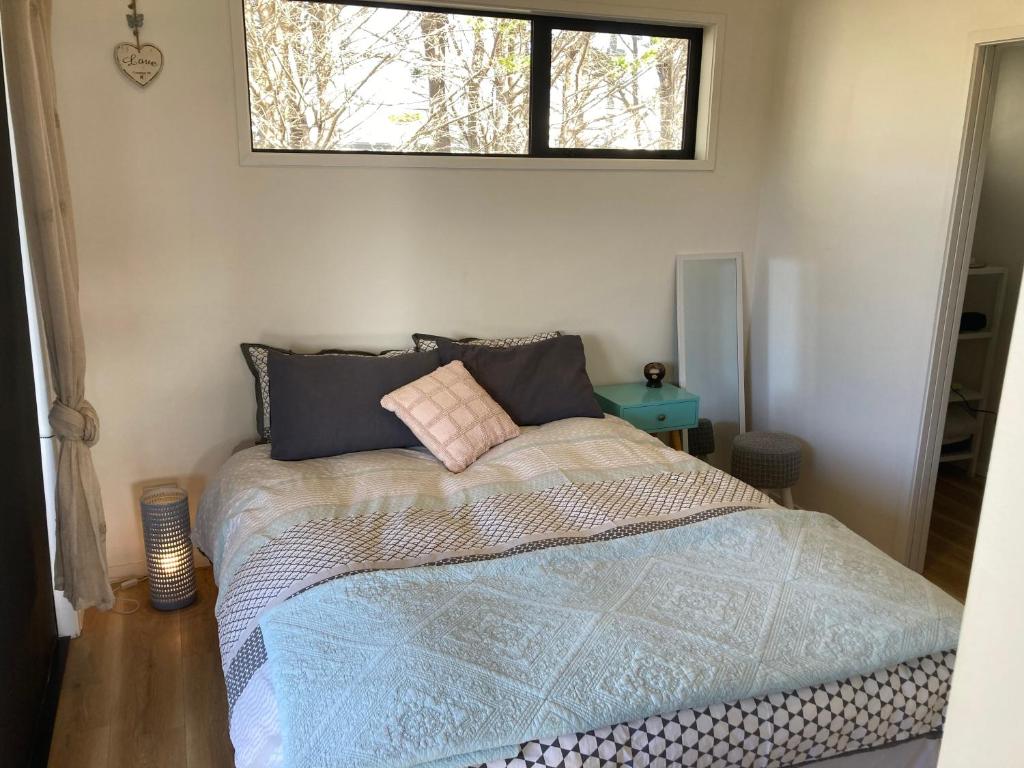 a bedroom with a bed with a window above it at Harmony at the Heads in Mangawhai