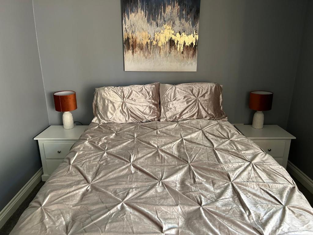 a bed with a silver comforter in a bedroom at The Village apartment. in Marton