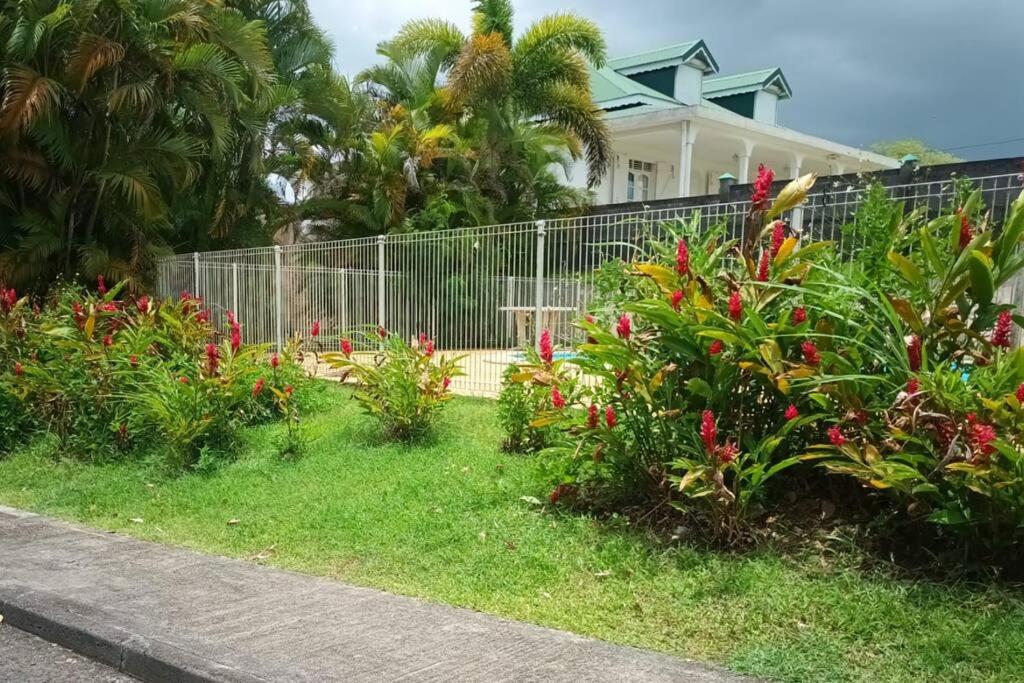 a fence in front of a house with flowers at Grand appartement duplex in Baie-Mahault