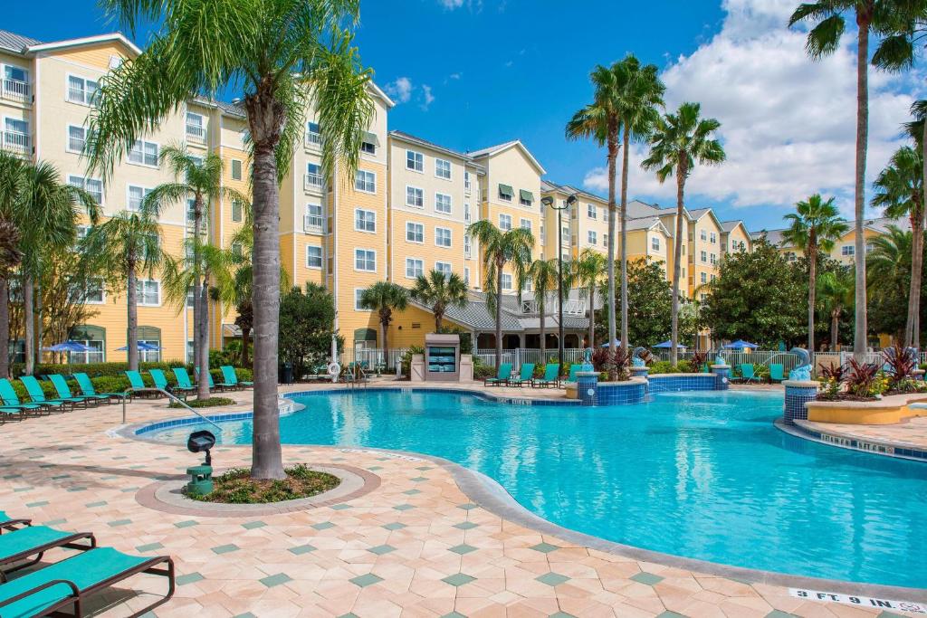a swimming pool with palm trees in front of a building at Residence Inn by Marriott Orlando at SeaWorld in Orlando