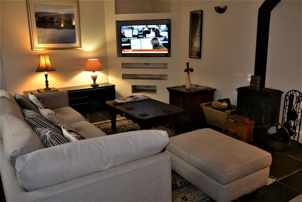 a living room with a couch and a flat screen tv at Hillfields Farm Barn - A Rural Equestrian Escape in Coventry