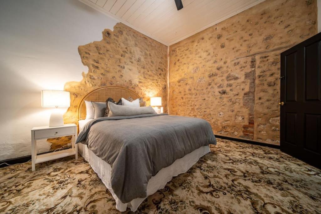 - une chambre avec un grand lit et un mur en pierre dans l'établissement Blacksmith Cottage Aldinga, à Aldinga