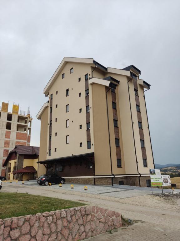 Un gran edificio con un coche aparcado delante. en Green Forest Lux Apartman, en Zlatibor