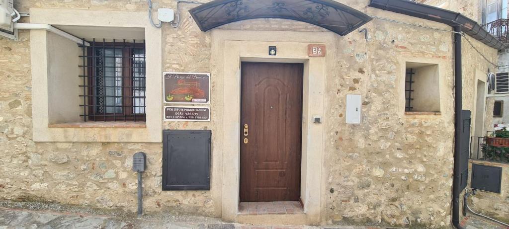 a stone building with a brown door with a sign on it at IL BORGO DEL BENESSERE in Rocca Imperiale
