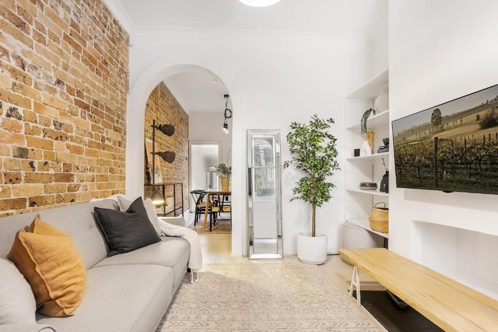 a living room with a white couch and a brick wall at Surry Hills l 2 Bedroom Terrace Home in Sydney