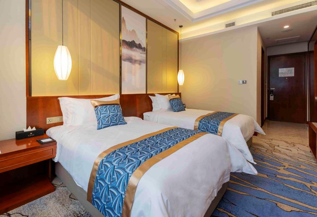 a hotel room with two beds and a desk at YunRay Hotel Shijiazhuang in Shijiazhuang