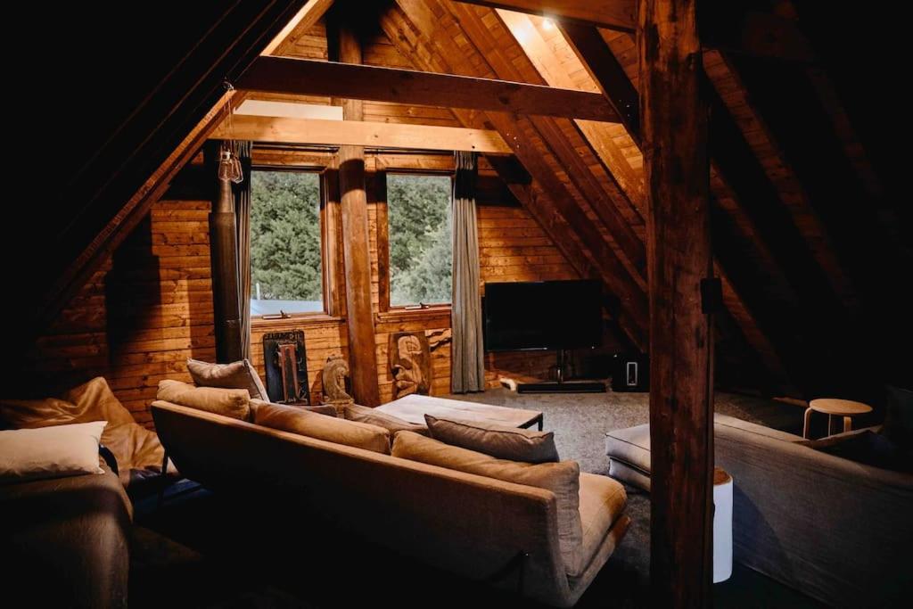 uma sala de estar com um sofá grande numa cabina em The Maple Lodge with Alpacas, Goats, Chickens, Boars, Wild Ducks & Outdoor Pizza Oven em Robertson
