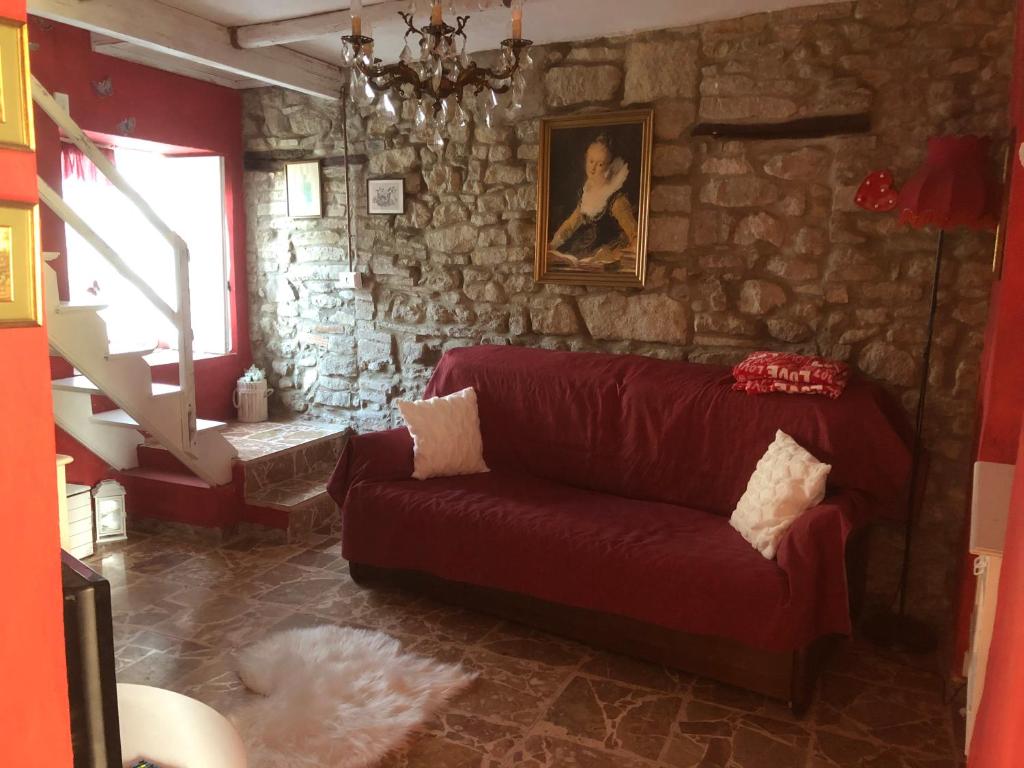 a living room with a red couch and a stone wall at JOLIE PETITE MAISON chez Barbara in Garbagna