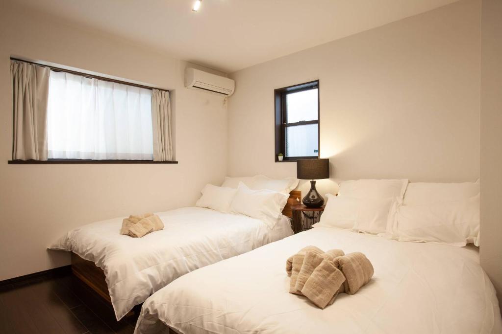 duas camas num quarto com lençóis brancos e uma janela em KS west Waseda 2F em Tóquio