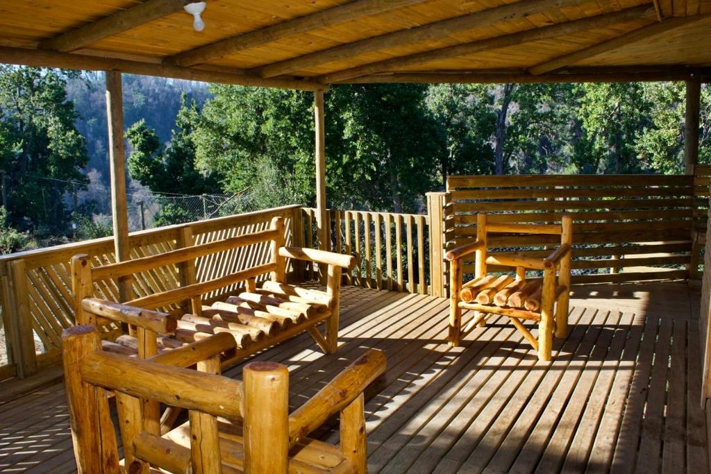deux bancs en bois assis sur une terrasse en bois dans l'établissement Cabañas oasis, radal 7 tazas, à El Torreón