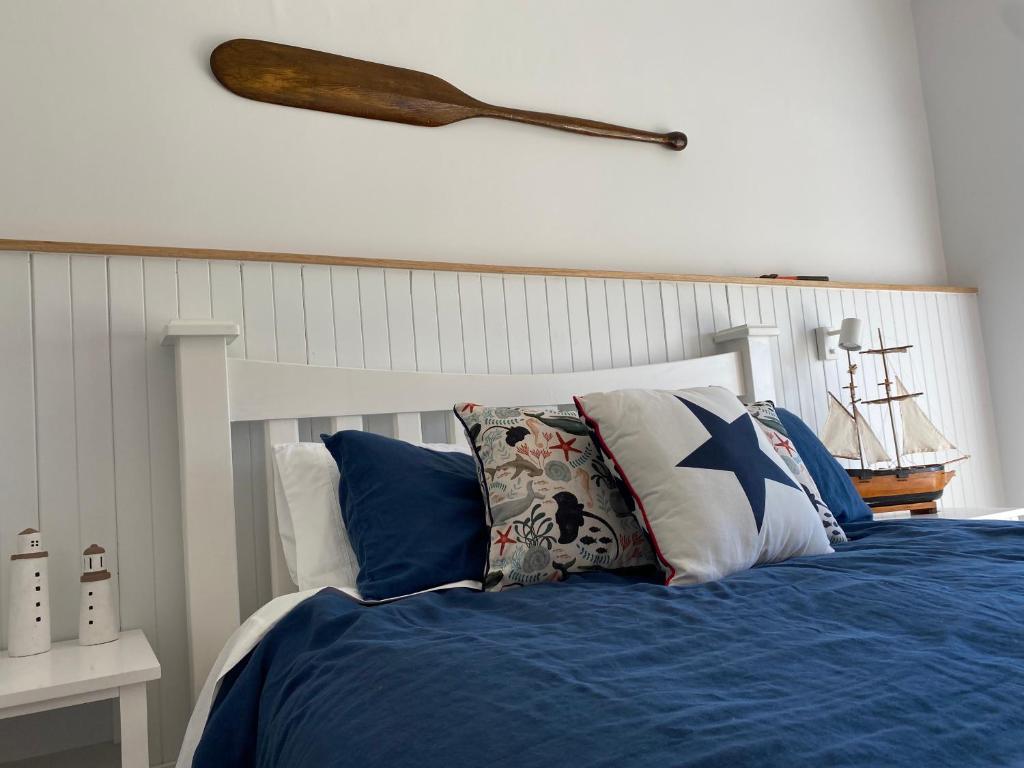 a bedroom with a bed with blue sheets and a wooden bat on the wall at Windspray Cottage in Port Albert