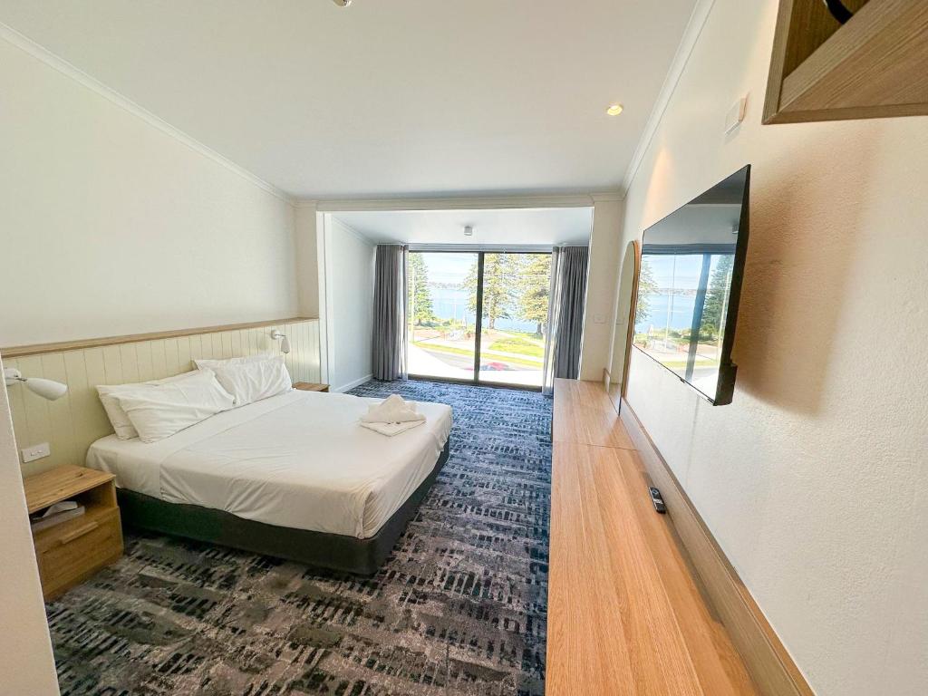 a hotel room with a bed and a window at Pippi's at the Point in Warners Bay