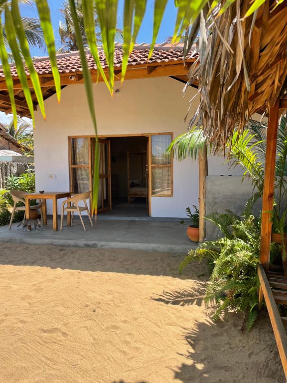 a house on the beach with a table and chairs at Gypsea Cabana in Arugam Bay