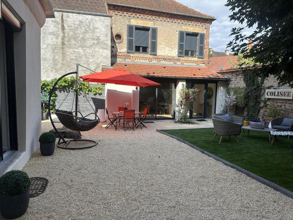 une terrasse avec des chaises et une table avec un parasol rouge dans l'établissement Gîte Moulins, 2 pièces, 2 personnes - FR-1-489-474, à Moulins