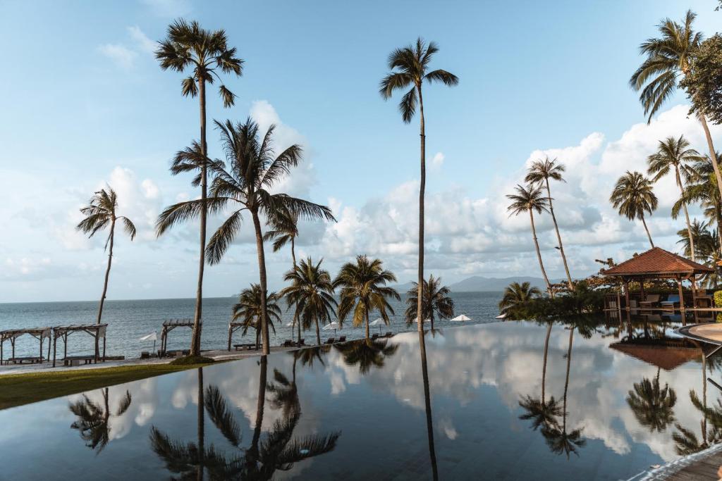 una piscina con palmeras y el océano en Napasai, A Belmond Hotel, Koh Samui, en Mae Nam