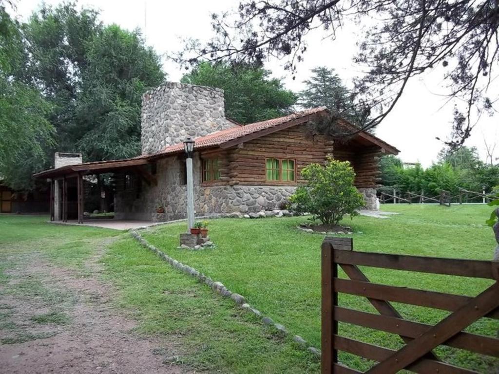 a log cabin with a fence in front of it at Cabañas Mc Charlie in Santa Rosa de Calamuchita