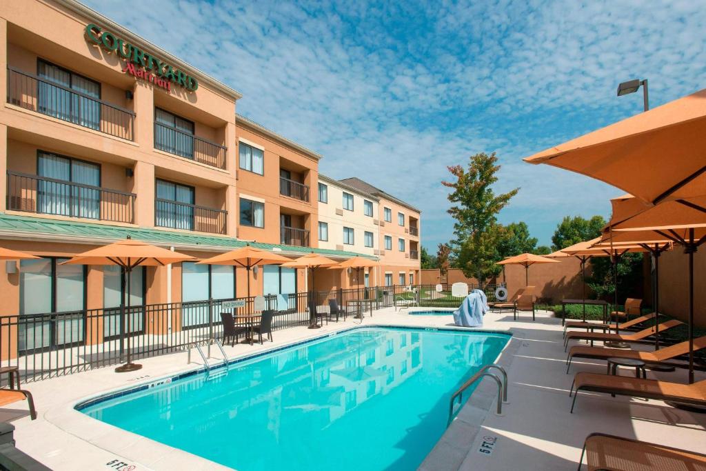 una piscina en un hotel con mesas, sillas y sombrillas en Courtyard by Marriott Montgomery Prattville, en Prattville