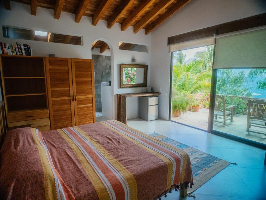 um quarto com uma cama e uma grande janela em Casa de la Luna em Puerto Escondido