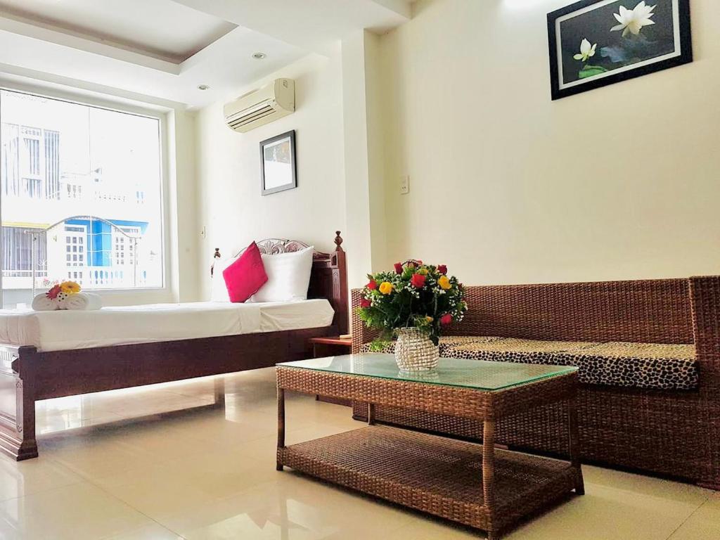 a living room with a bed and a table with flowers at Q.MIN apartment in Nha Trang