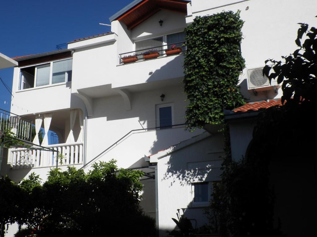 a white building with ivy on the side of it at Apartments - Rooms VESNA in Primošten