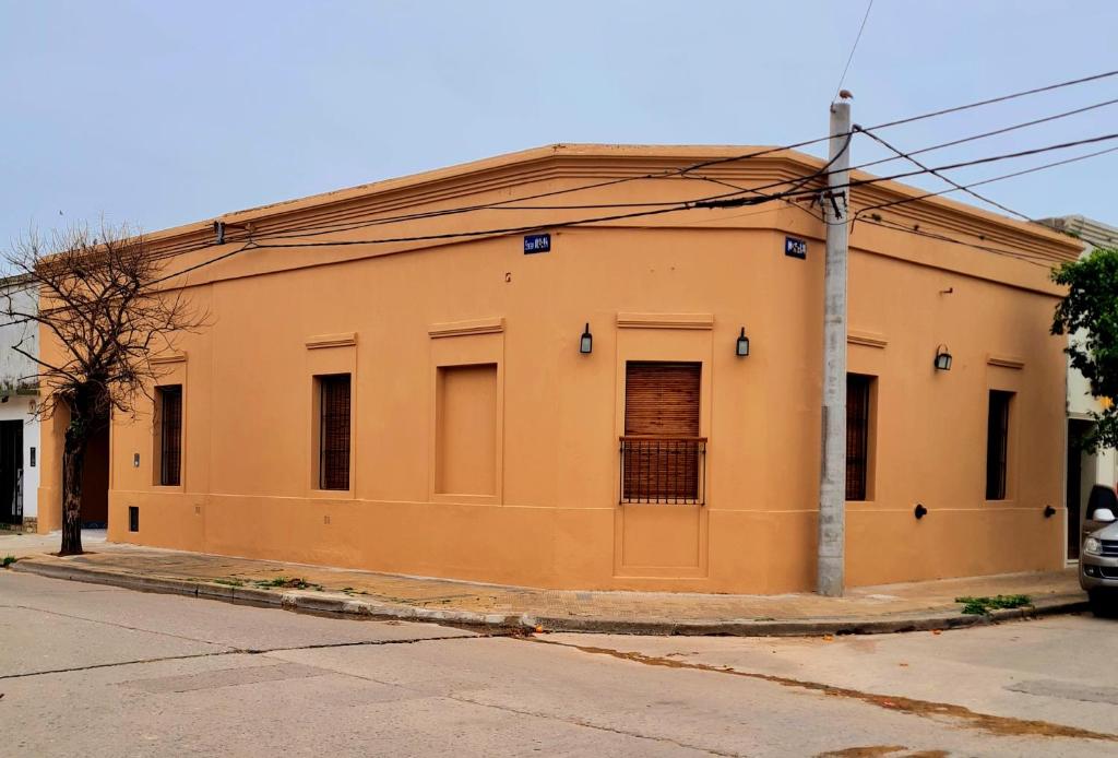 ein orangefarbenes Gebäude an der Straßenseite in der Unterkunft Lechuza Alvear in San Antonio de Areco