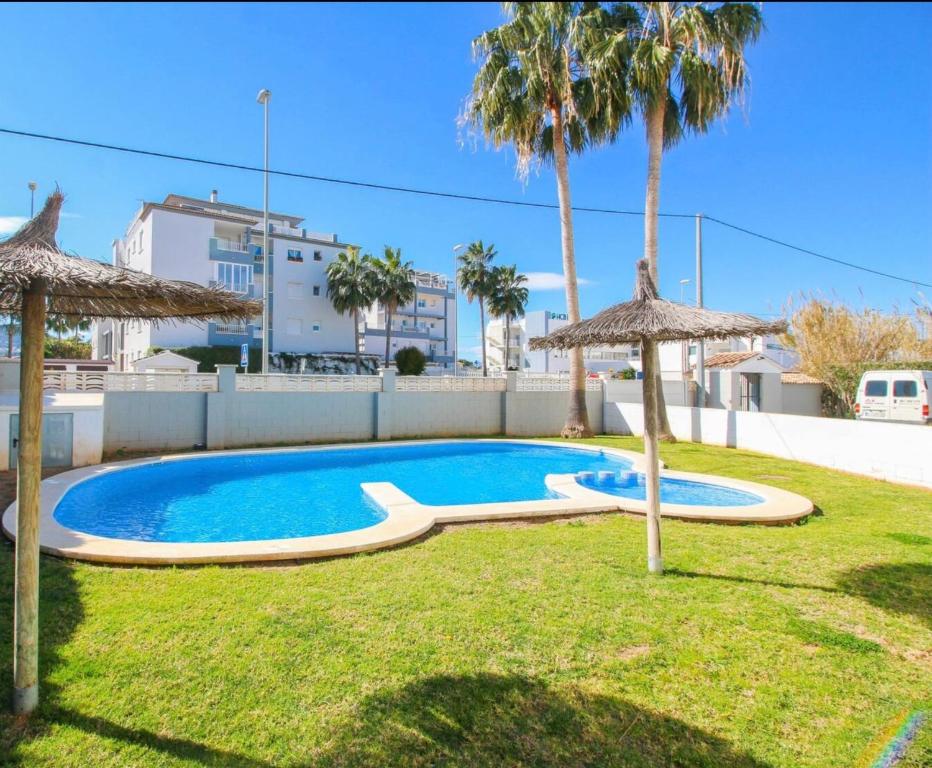 una piscina en un patio con 2 sombrillas en Apartamento con terraza y acceso directo a piscina, en Denia