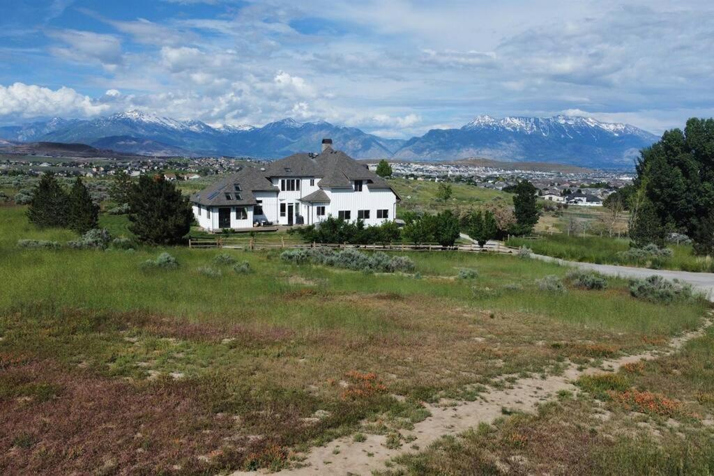 uma casa branca num campo com montanhas ao fundo em Ranch Mansion 6 Acres & 360 Mnt Views & Hiking! em Eagle Mountain