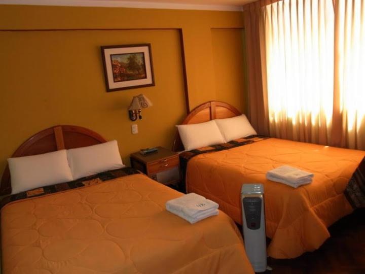 a hotel room with two beds and a window at Puno Wasi Hotel in Puno