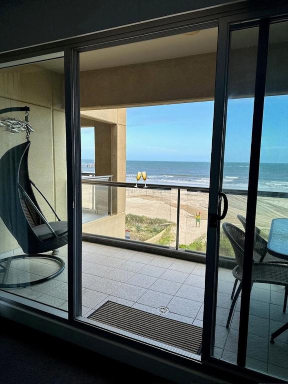 a room with a view of the ocean from a balcony at Absolute Beachfront at the Pier Glenelg in Adelaide
