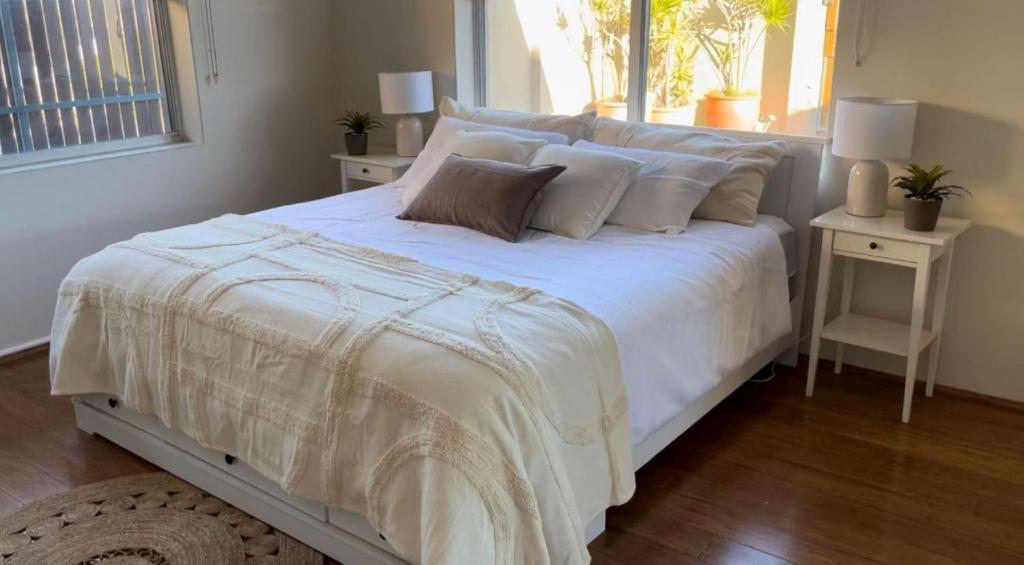 a bedroom with a white bed and a window at Banyan, 14 Montevideo Parade - spacious pet friendly property with air con and free WiFi in Nelson Bay