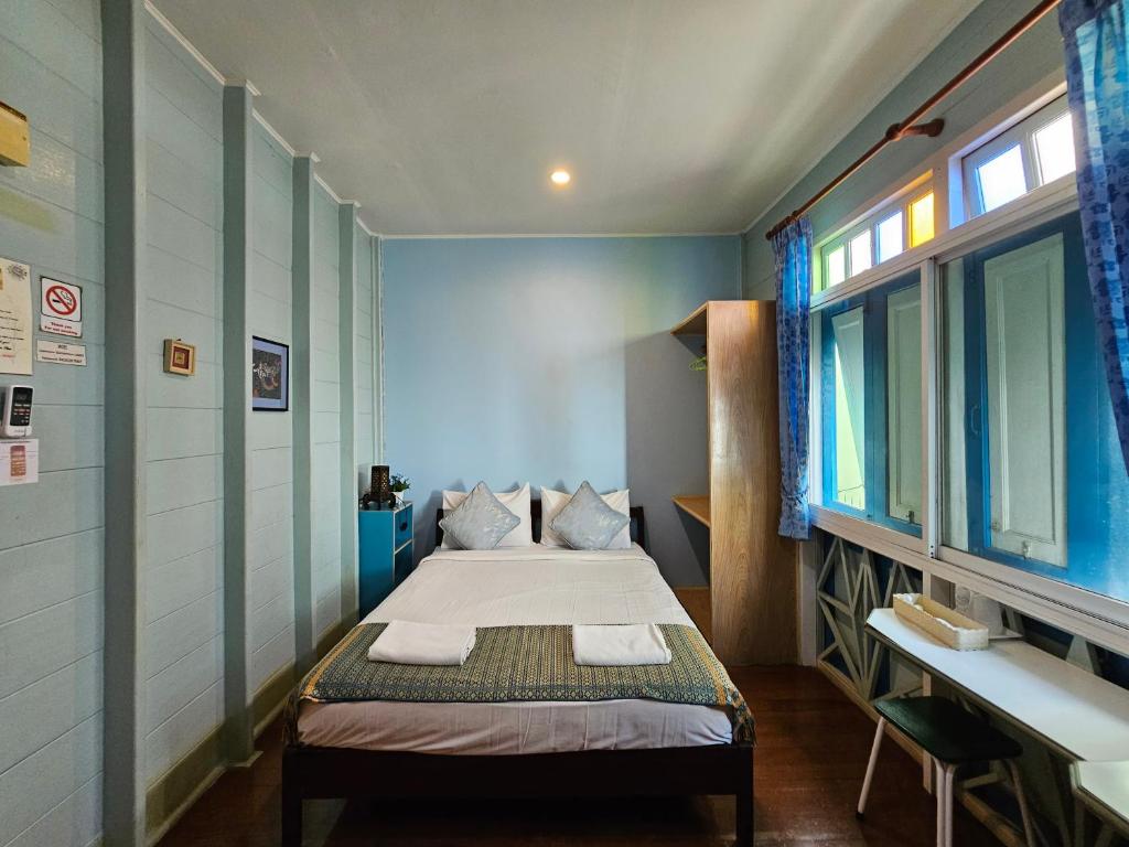 een kleine slaapkamer met een bed, een bureau en een raam bij Samsen Sam Place in Bangkok