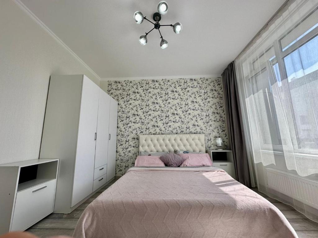 1 dormitorio con 1 cama grande con manta rosa en Grand Turan , Turan 43, en Taldykolʼ