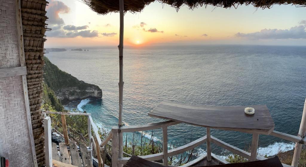 een uitzicht op de oceaan vanuit een huis met een stoel bij Eco Tourist Dream Stay Tree House in Nusa Penida