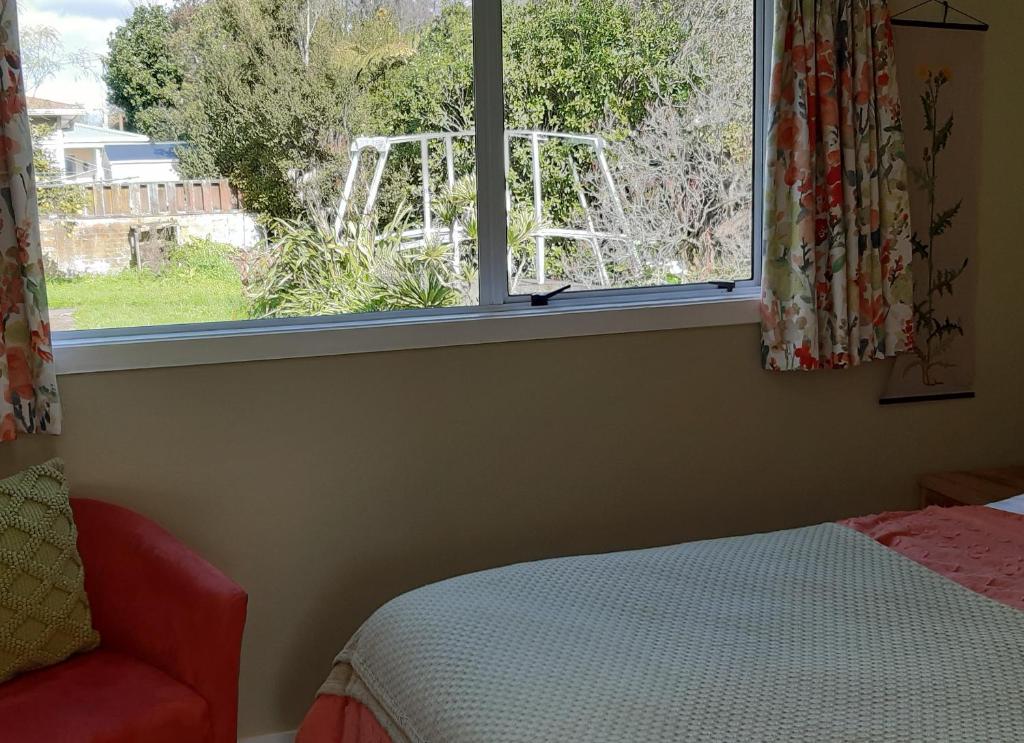 a bedroom with a window with a bed and a chair at Bunny Cottage in Masterton