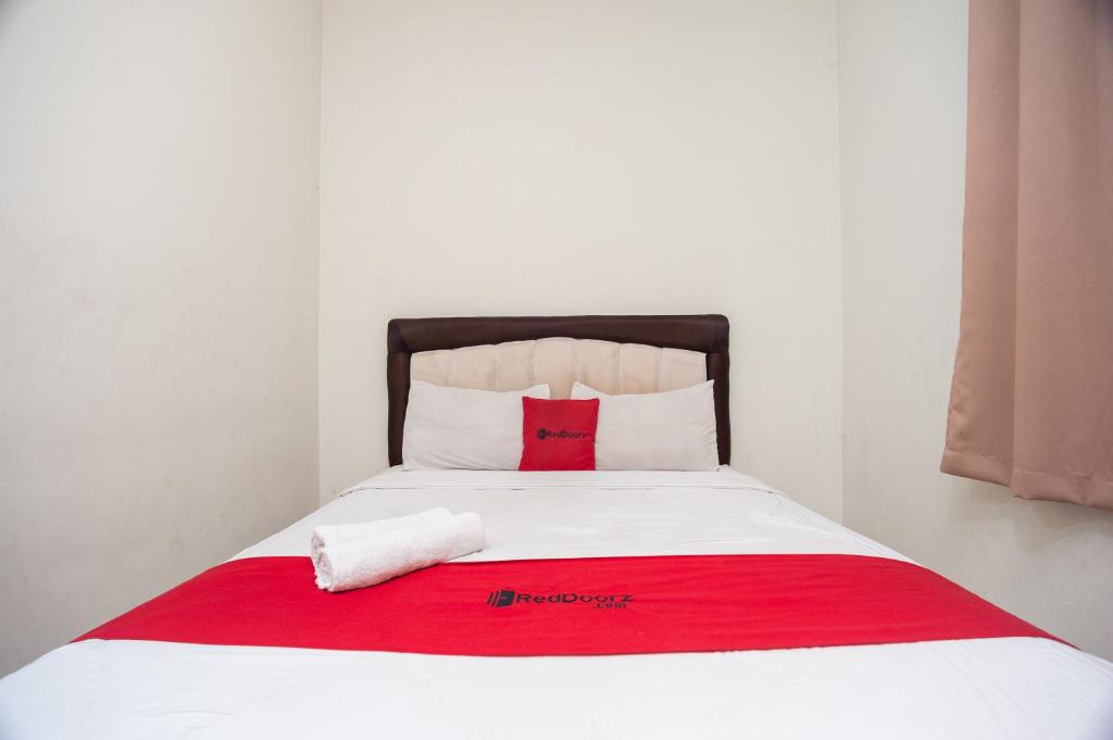 uma cama com um cobertor vermelho e branco em RedDoorz Plus near RS PMI Bogor em Bogor
