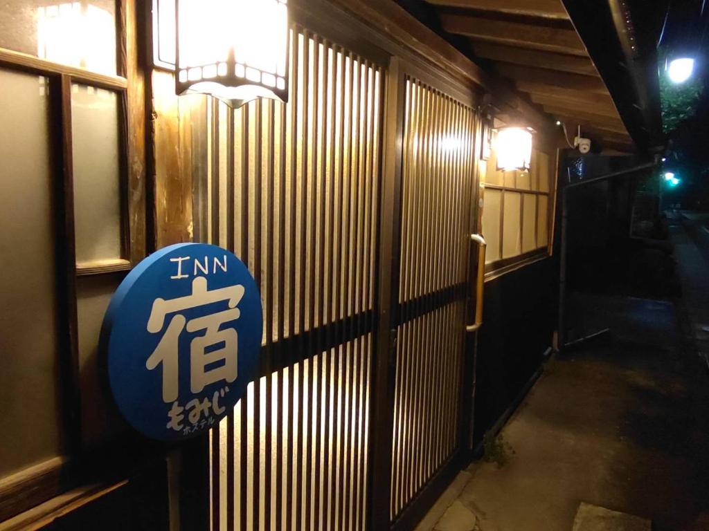 um sinal na lateral de um edifício em Momiji hostel em Minami Aso