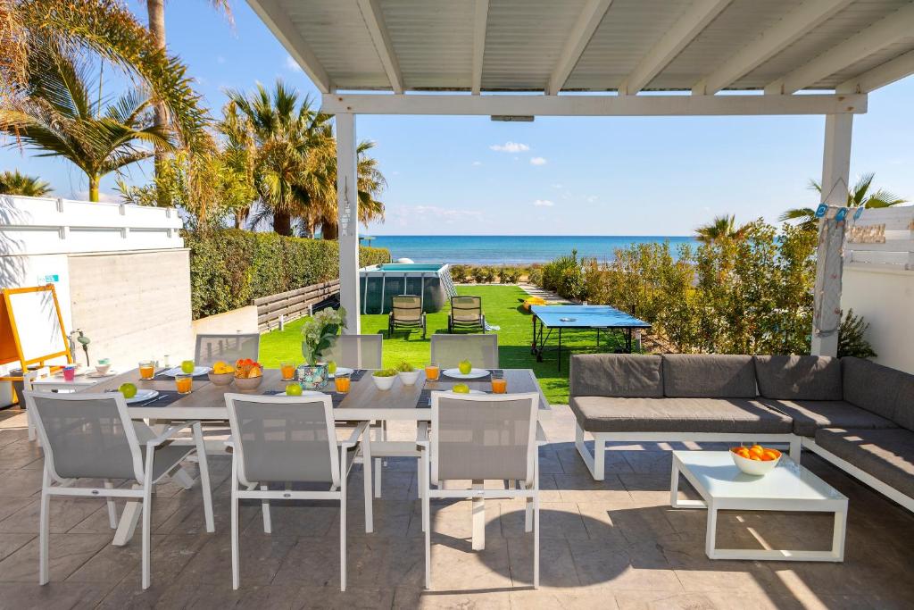 een patio met een tafel en stoelen en de oceaan bij Ayia Thekla Seafront Villa Dagi in Ayia Napa
