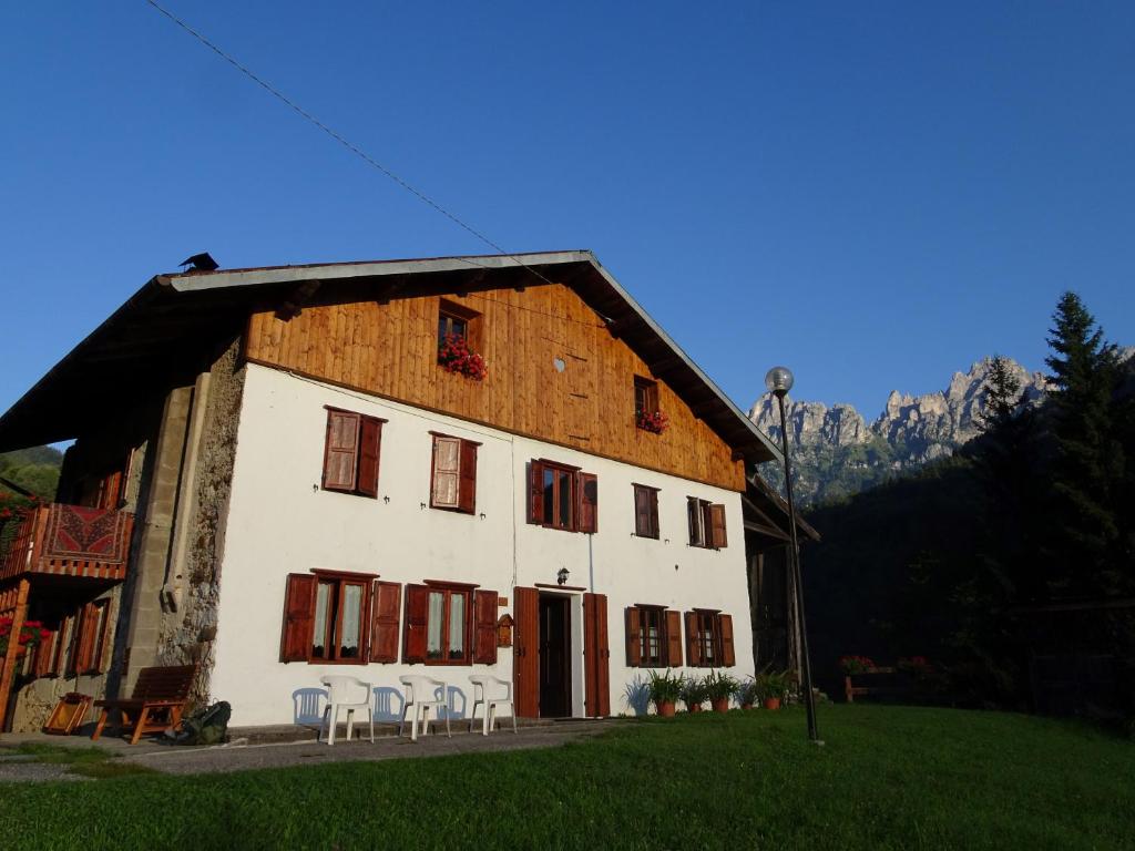 a large white building with chairs in front of it at B&B DOLOMIA in Sagron Mis