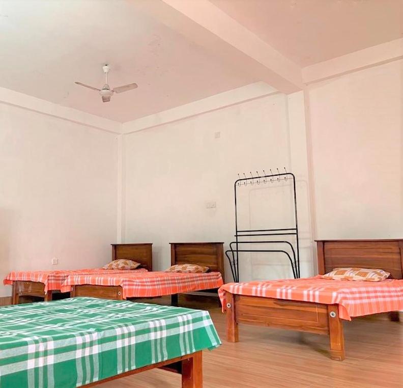 a room with three beds and a ceiling at Moderncore Hostel in Anuradhapura