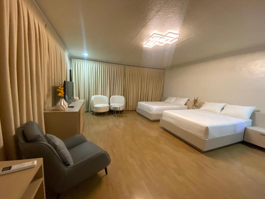 a hotel room with two beds and a chair at Honey Suite Room Inside Bee Cafe Cebu at Ayala Area in Cebu City