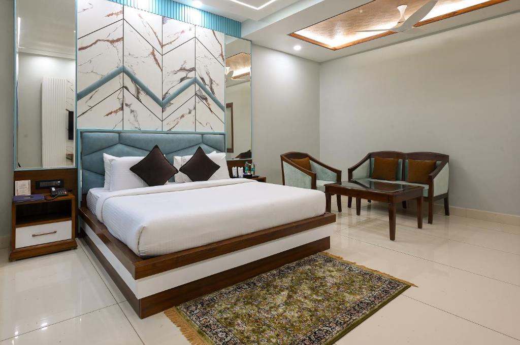 een slaapkamer met een bed, een tafel en een stoel bij Hotel Leela Grande in Karnāl