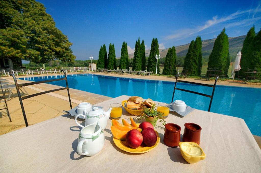 uma mesa com um prato de frutas ao lado de uma piscina em Domaine de Majastre em Bauduen